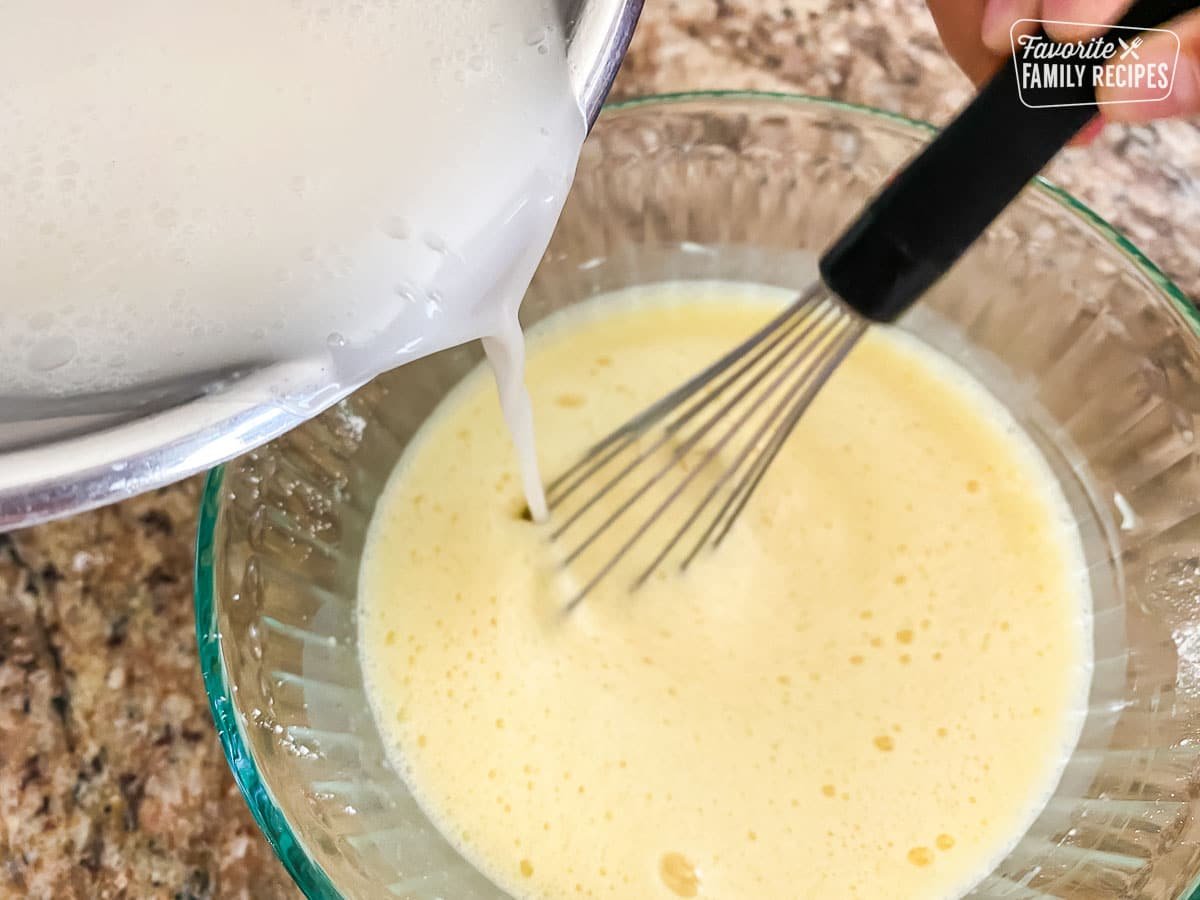 Coconut cream being poured into an egg mixture to make filling to Malasadas