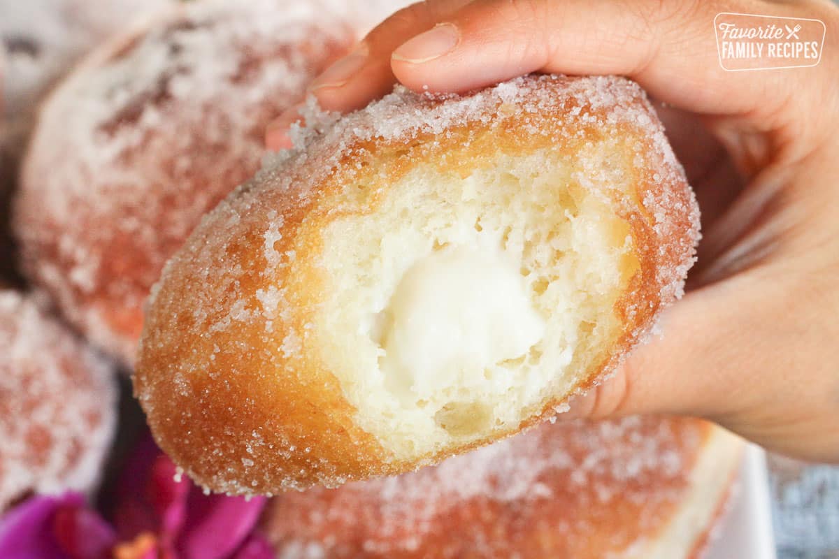 A close up of a malasada showing the coconut haupia filling inside