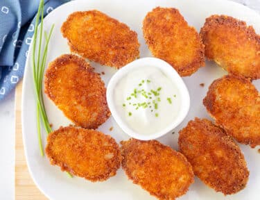 Platter of Parmesan Crusted Potatoes with a dish of sour cream and chives.