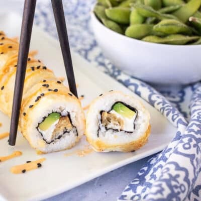 Chop sticks picking up a piece of a Shrimp Tempura Roll.
