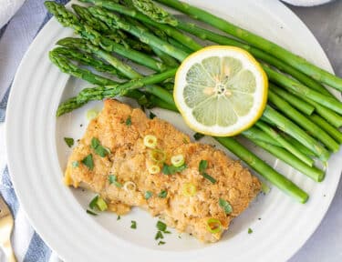 Plate of asparagus with a fillet of Baked Mahi Mahi with Parmesan Crust.