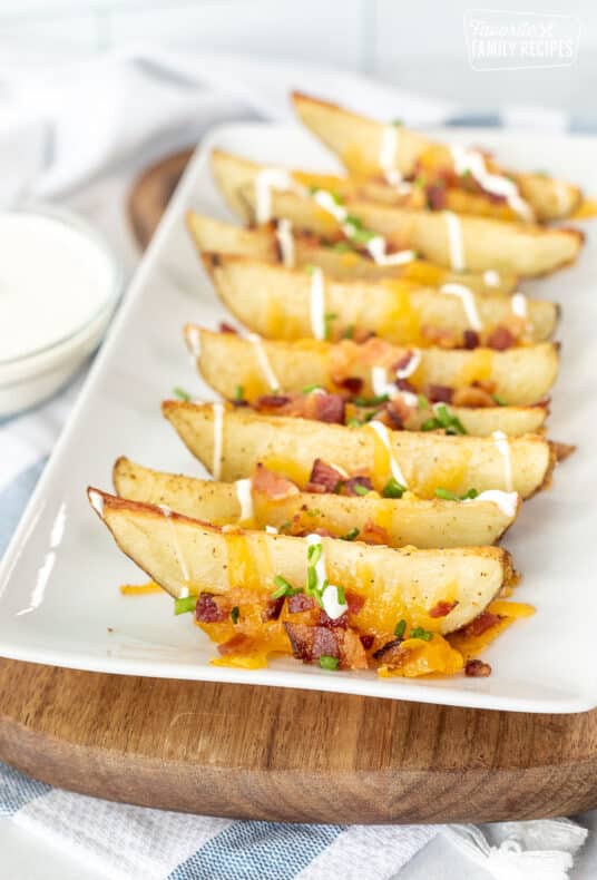 Loaded Potato Wedges on a platter with bacon, cheese, chives and sour cream.