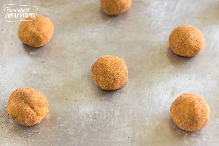 balls of cookie dough rolled in cinnamon sugar on a baking sheet.