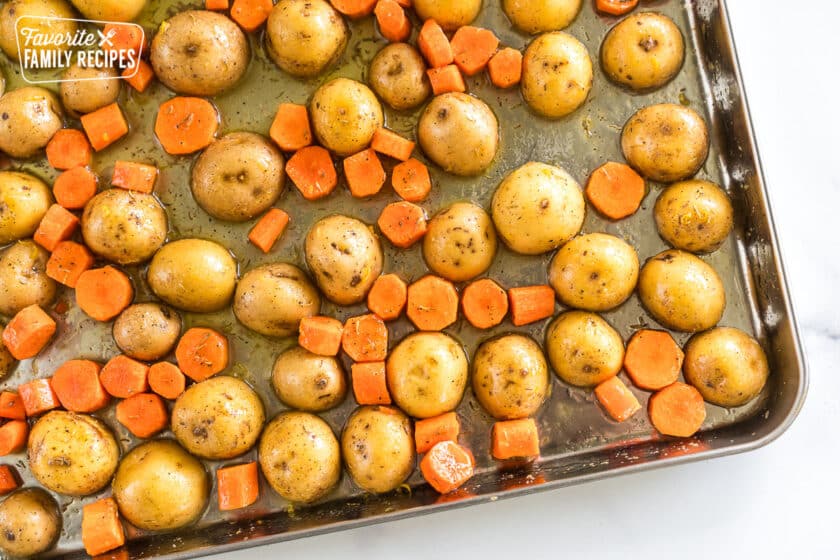 seasoned potatoes and carrots on a baking sheet before going in the oven