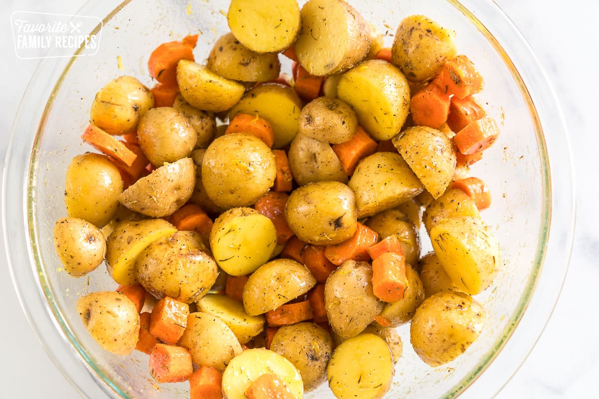 chopped potatoes and carrots in a bowl with oil and seasonings