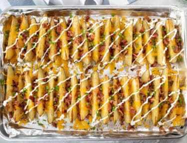 Cookie Sheet of Loaded Potato Wedges with bacon, cheese, chives and sour cream.