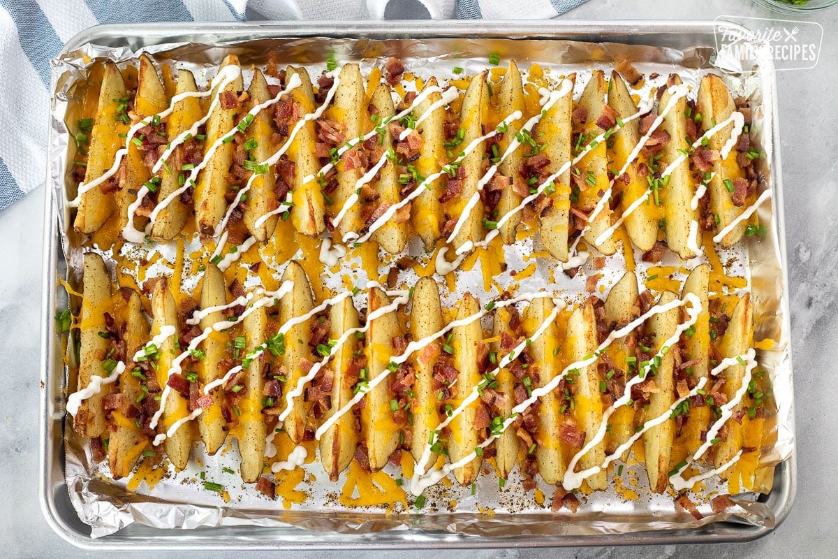 Cookie Sheet of Loaded Potato Wedges with bacon, cheese, chives and sour cream.