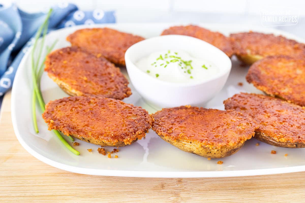 Parmesan Crusted Potatoes on a serving dish with sour cream.