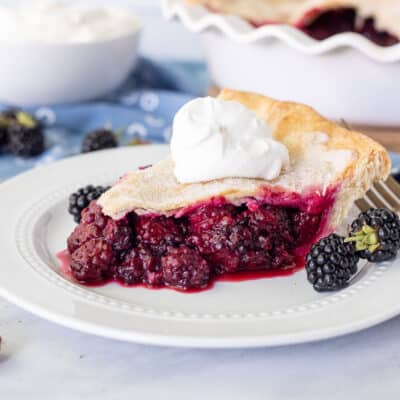Slice of Blackberry Pie with whipped cream on top.