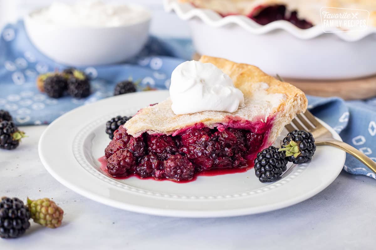 Slice of Blackberry Pie with whipped cream on top.