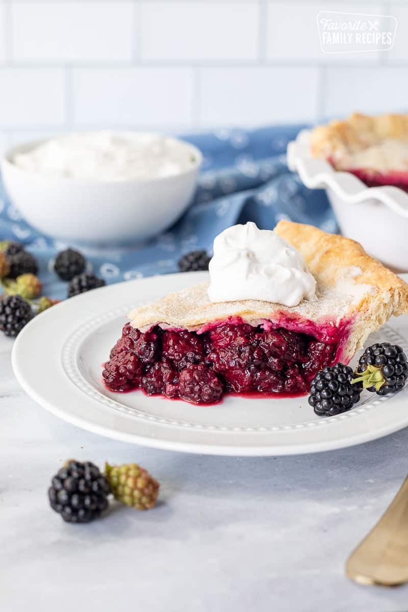 Slice of Blackberry Pie topped with whipped cream.