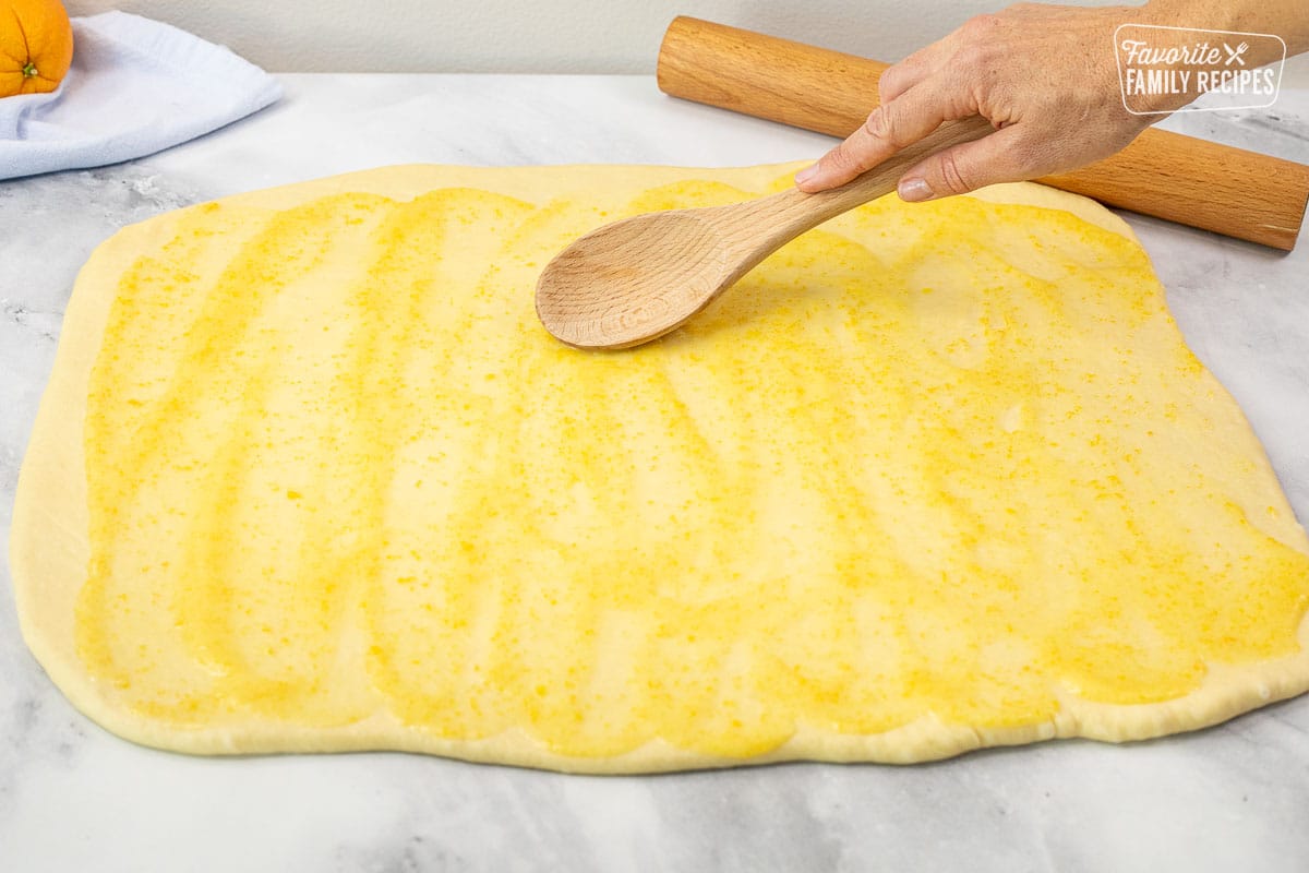 Spreading dough with Orange Sauce for Homemade Orange Rolls.