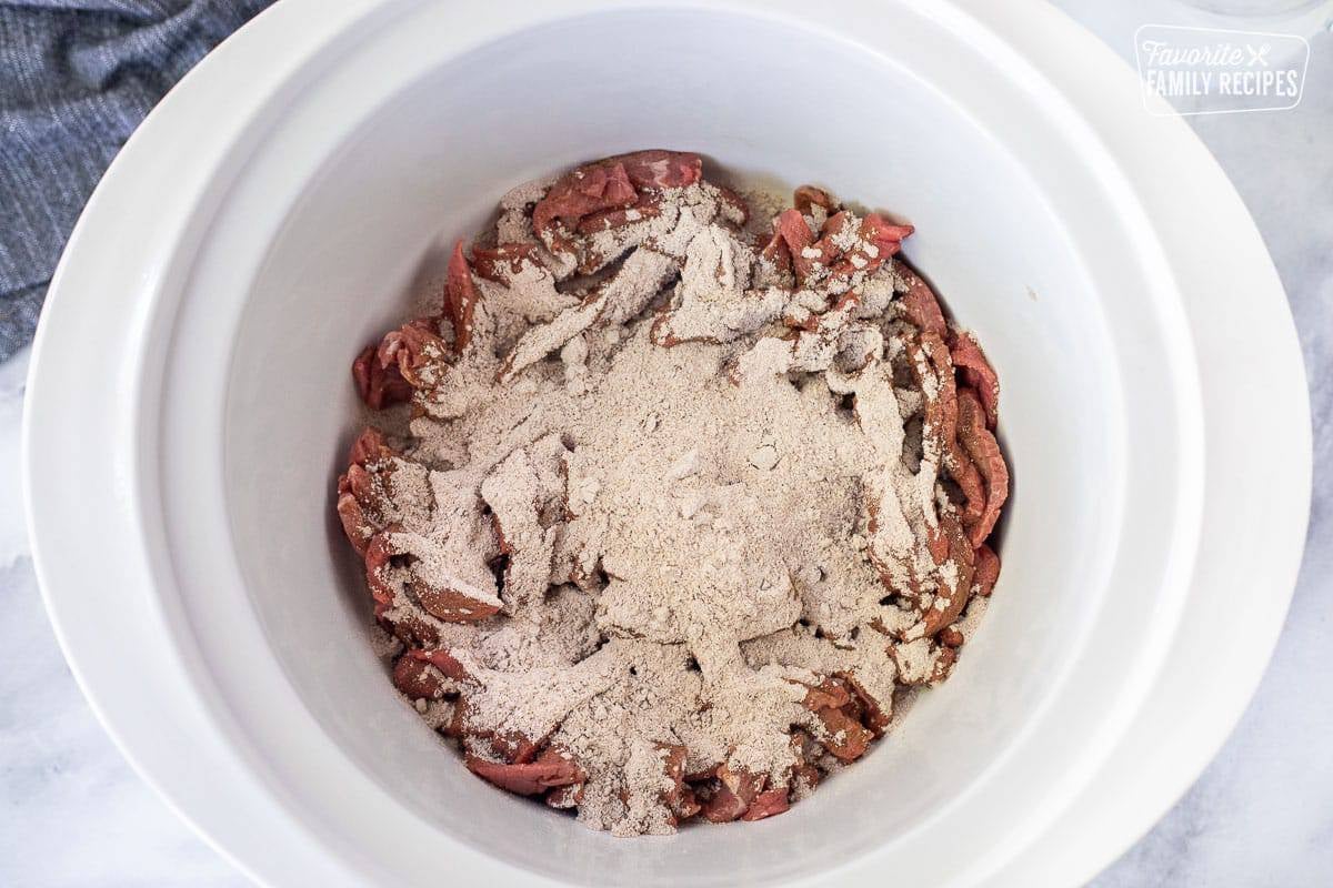 Crockpot with steak and dry gravy mixes on top.