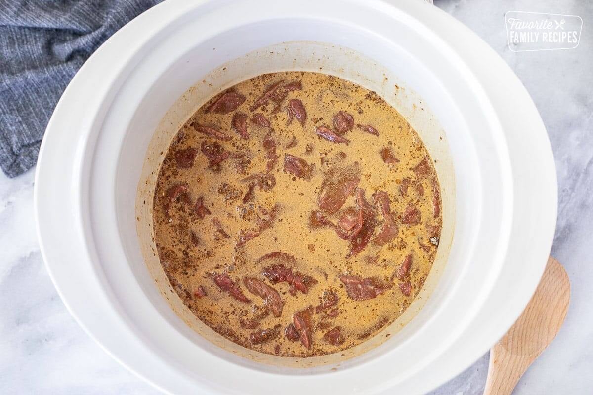 Crockpot with combined gravy mixes, water and steak.