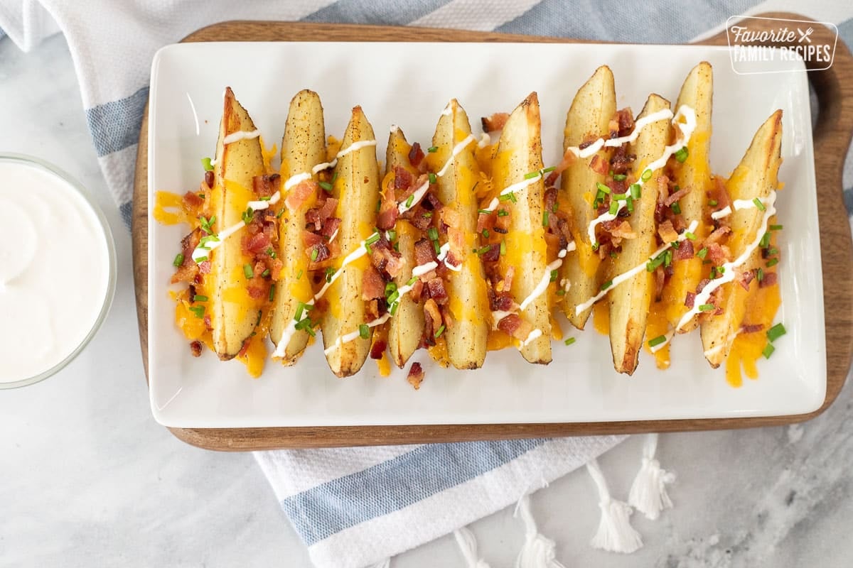 Plate with Loaded Potato Wedges next to extra sour cream.