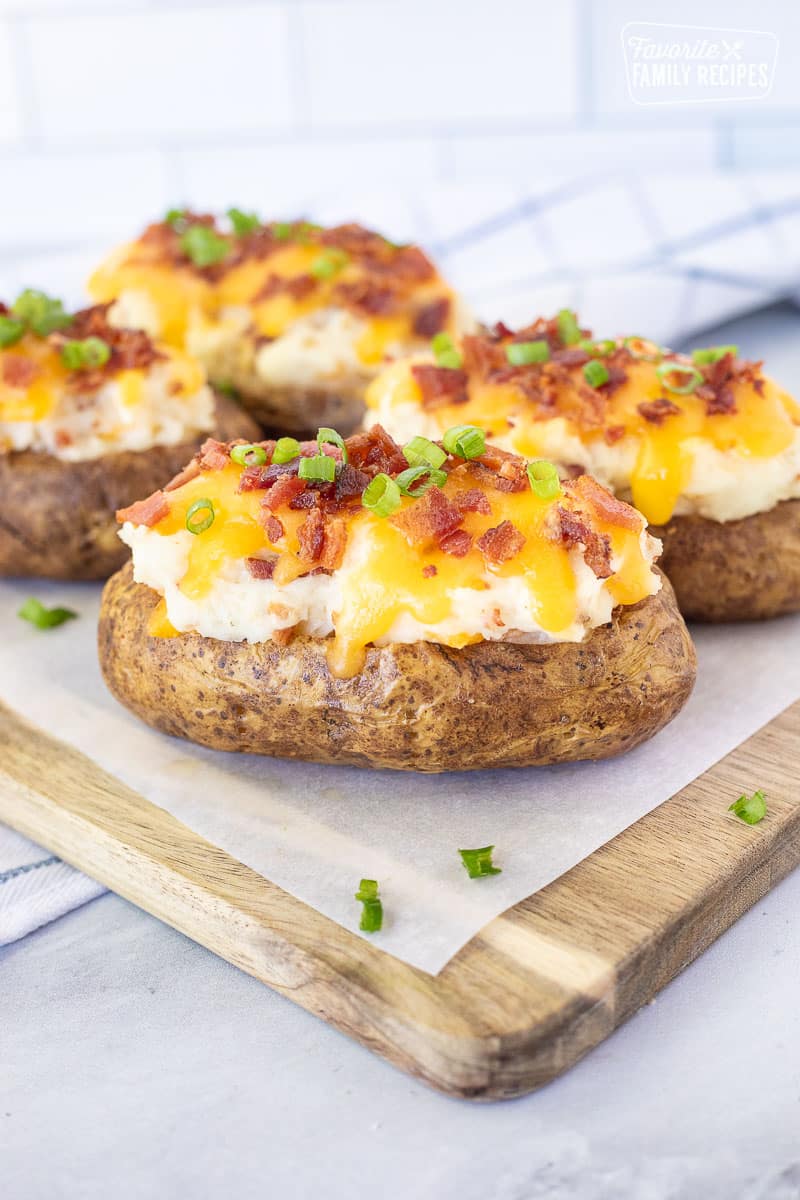 Twice Baked Potato on a cutting board loaded with cheese, bacon and green onion.