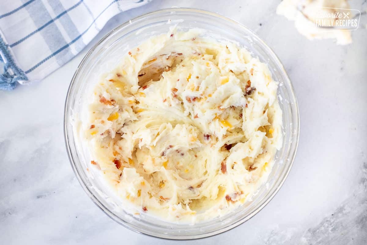 Bowl of mashed potatoes with cheese, bacon bits for Twice Baked Potatoes.