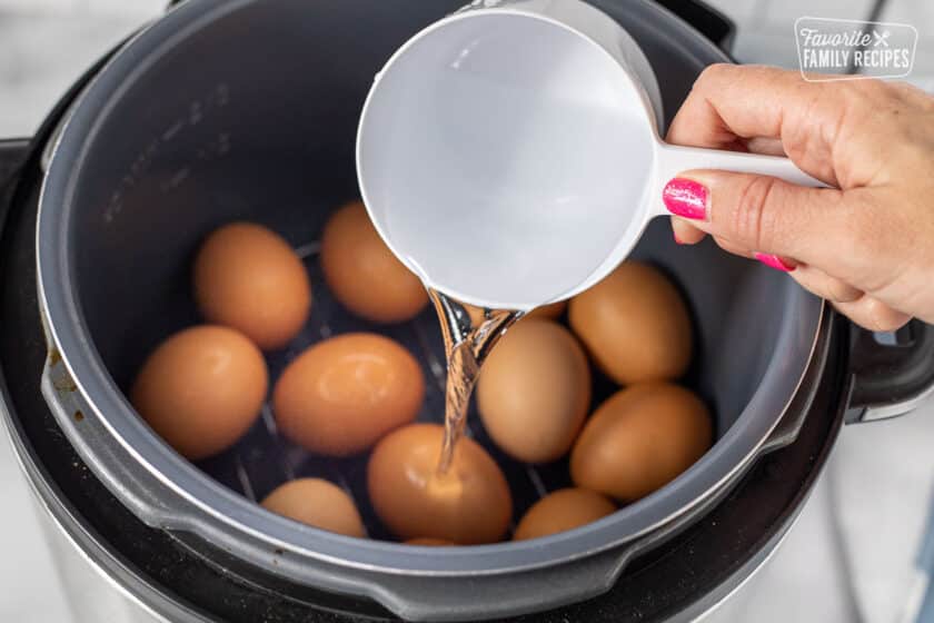 Water pouring into Instant Pot of eggs.