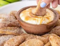Hand holding a Apple Fry and dipping it into caramel dip.