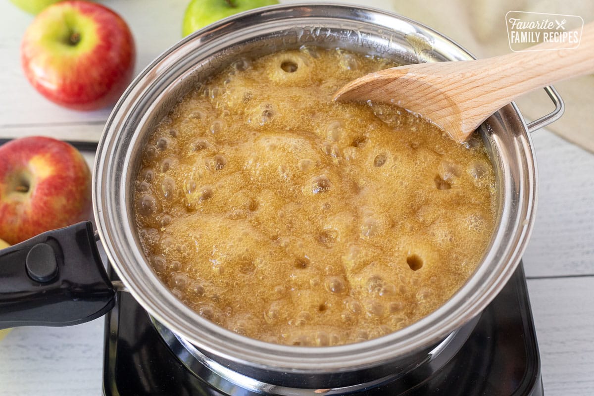 Pan boiling Caramel Apple Dip and stirring with a wooden spoon.