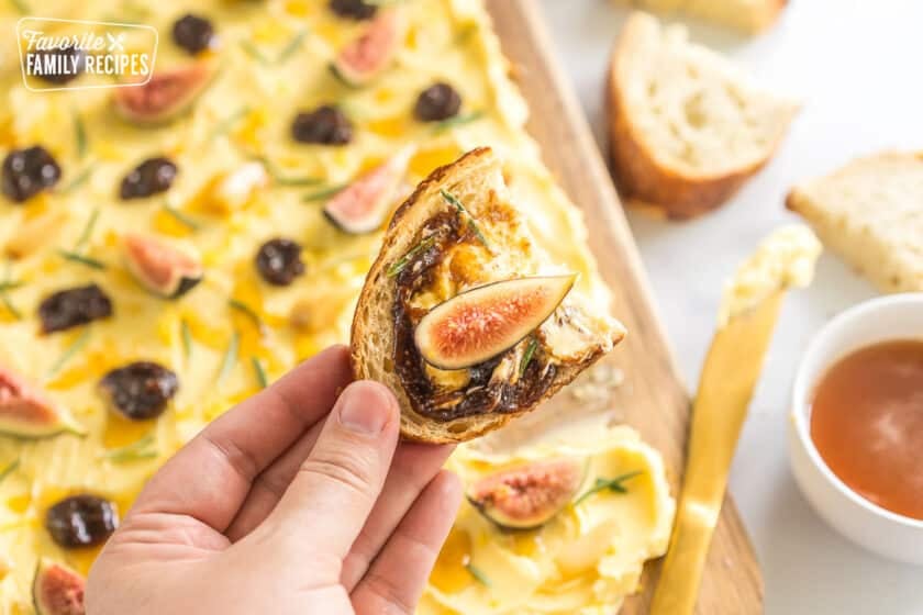 A slice of bread with butter, fig butter, rosemary and a fig slice