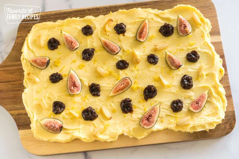 butter smeared on a wooden slab topped with lemon zest, salt, figs, fig butter, and roasted garlic