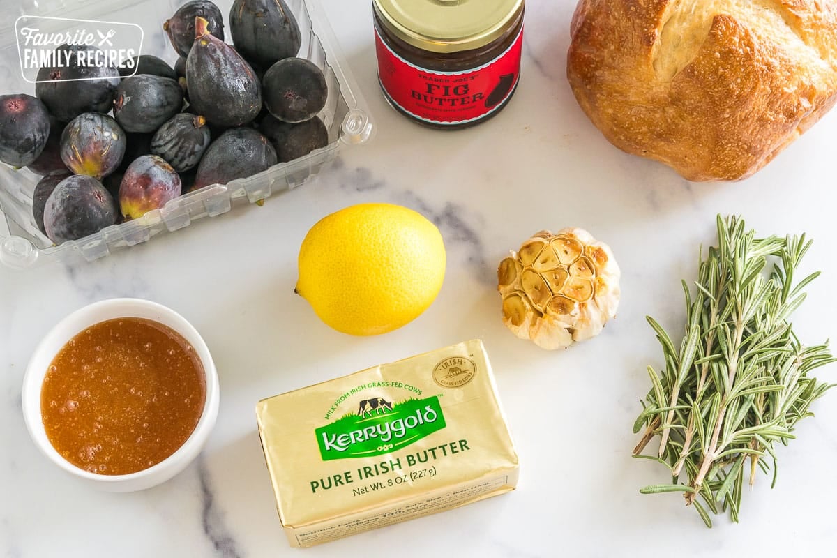 honey, figs, fig jam, bread, garlic, and rosemary on a counter