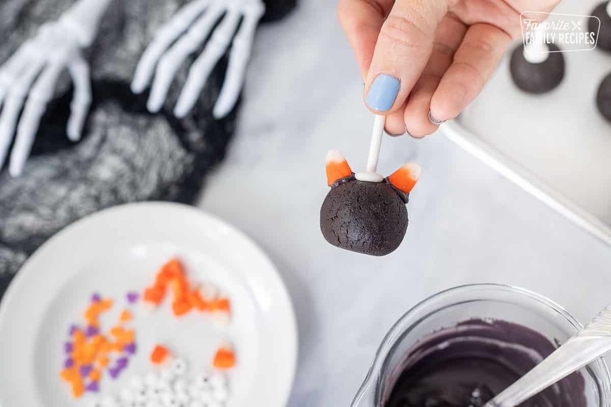 Candy corn ears attached with candy melts onto the cake pop for a black cat Halloween Cake Pop.