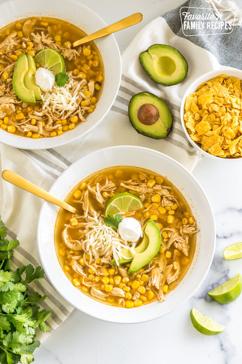 A bowl of chicken tortilla soup topped with lime, sour cream, cheese, and avocado.