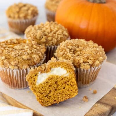 Close up of Pumpkin Cream Cheese Muffins on a cutting board with parchment paper.