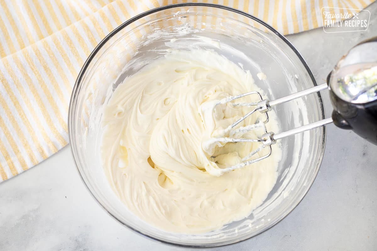 Bowl of Cream Cheese mixture with electric mixture for Pumpkin Cream Cheese Muffins.