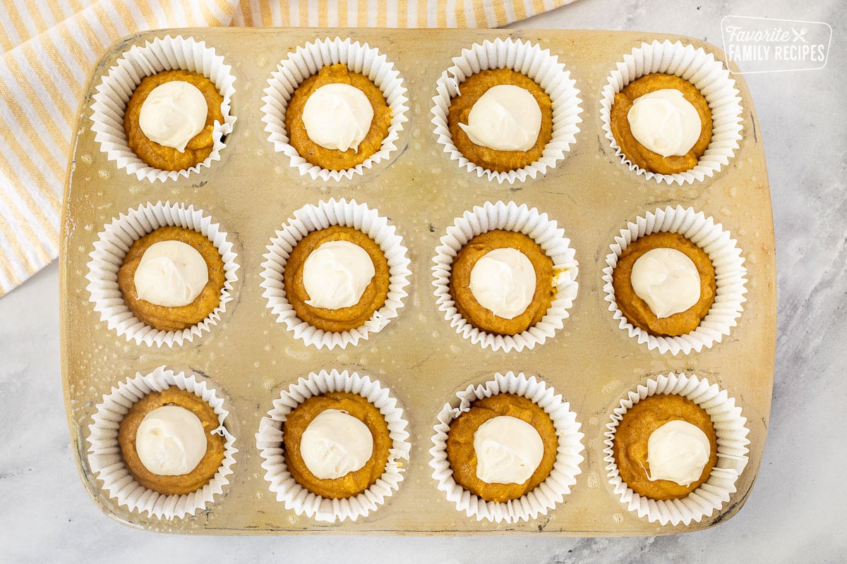 Cream cheese mixture on top of Pumpkin Muffin batter in pan.