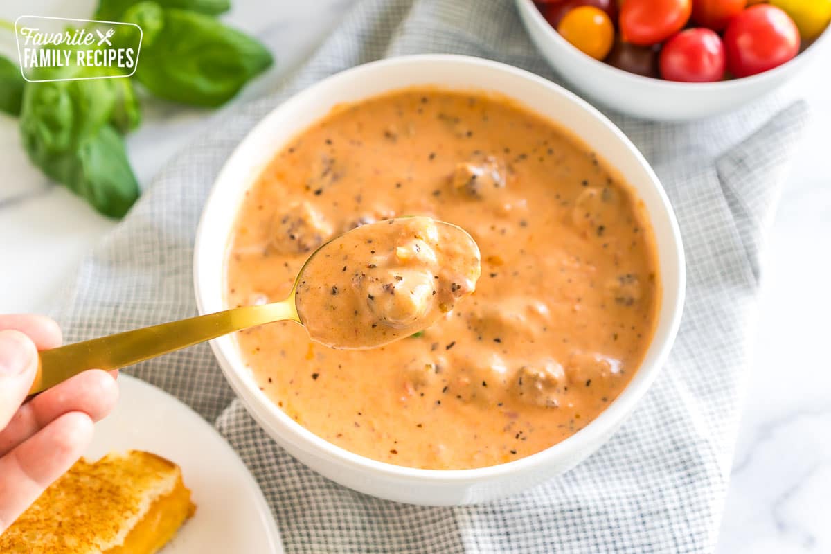 creamy tomato basil soup in a bowl with a spoonful being taken out