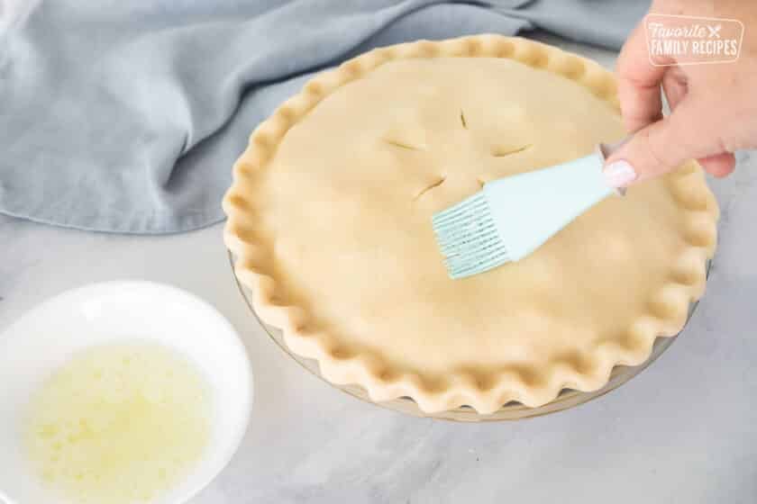 Brushing egg whites on top of Homemade Chicken Pot Pie.