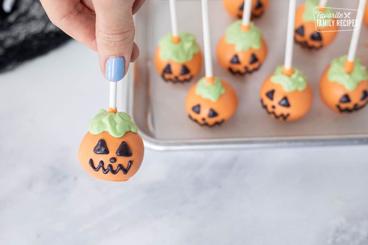 Piping face with black candy melts for pumpkin Halloween Cake pops.