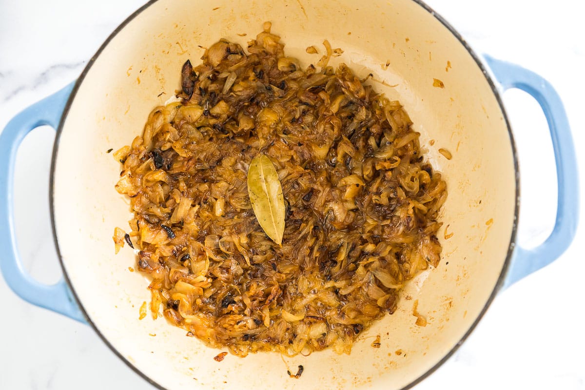 caramelized onions in a large pot with a bay leaf