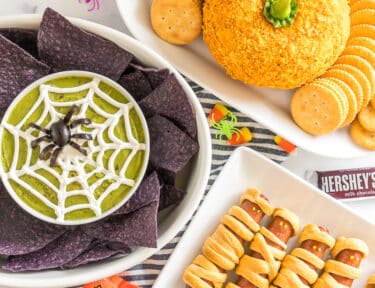 A spread of Halloween Appetizers on a table with halloween candy and spider rings