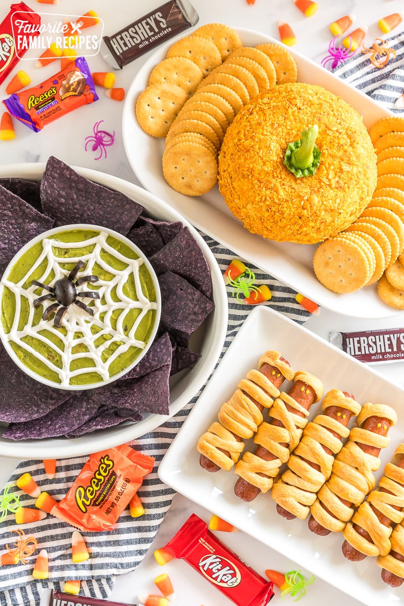 A spread of Halloween Appetizers on a table with halloween candy and spider rings.