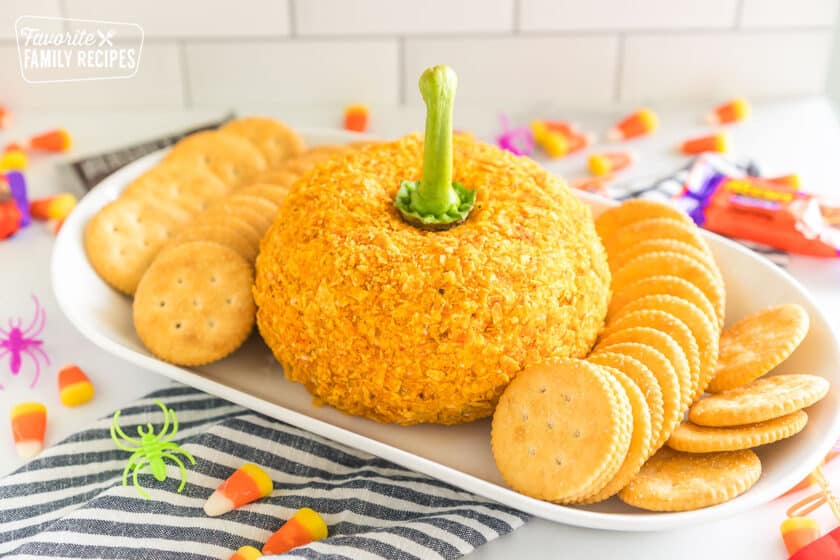 A cheese ball coated in crushed Doritos with a pepper stem sticking out to make it look like a pumpkin