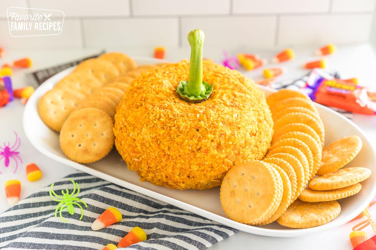 A cheese ball coated in crushed Doritos with a pepper stem sticking out to make it look like a pumpkin