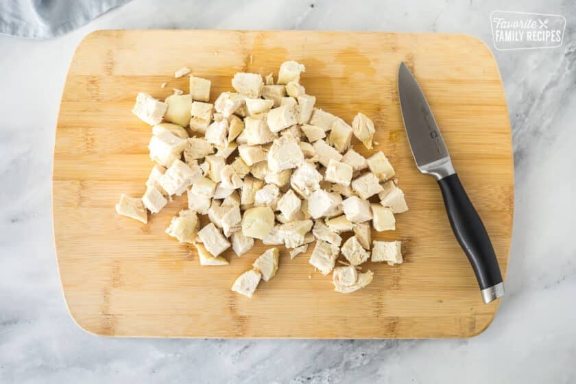 Cut up chicken on a cutting board for Homemade Chicken Pot Pie.