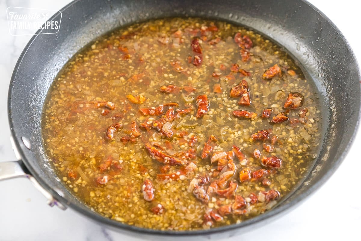 Shallots, garlic, chicken stock, and sun dried tomatoes in a skillet