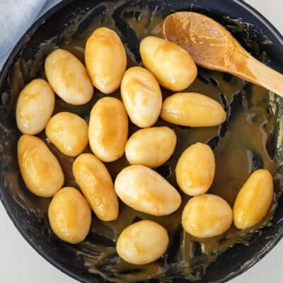 Mixing Brunede Kartofler in a skillet.