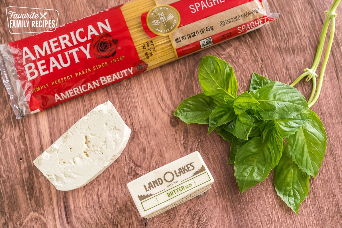 Spaghetti noodles, myzithra, butter, and basil on the counter.