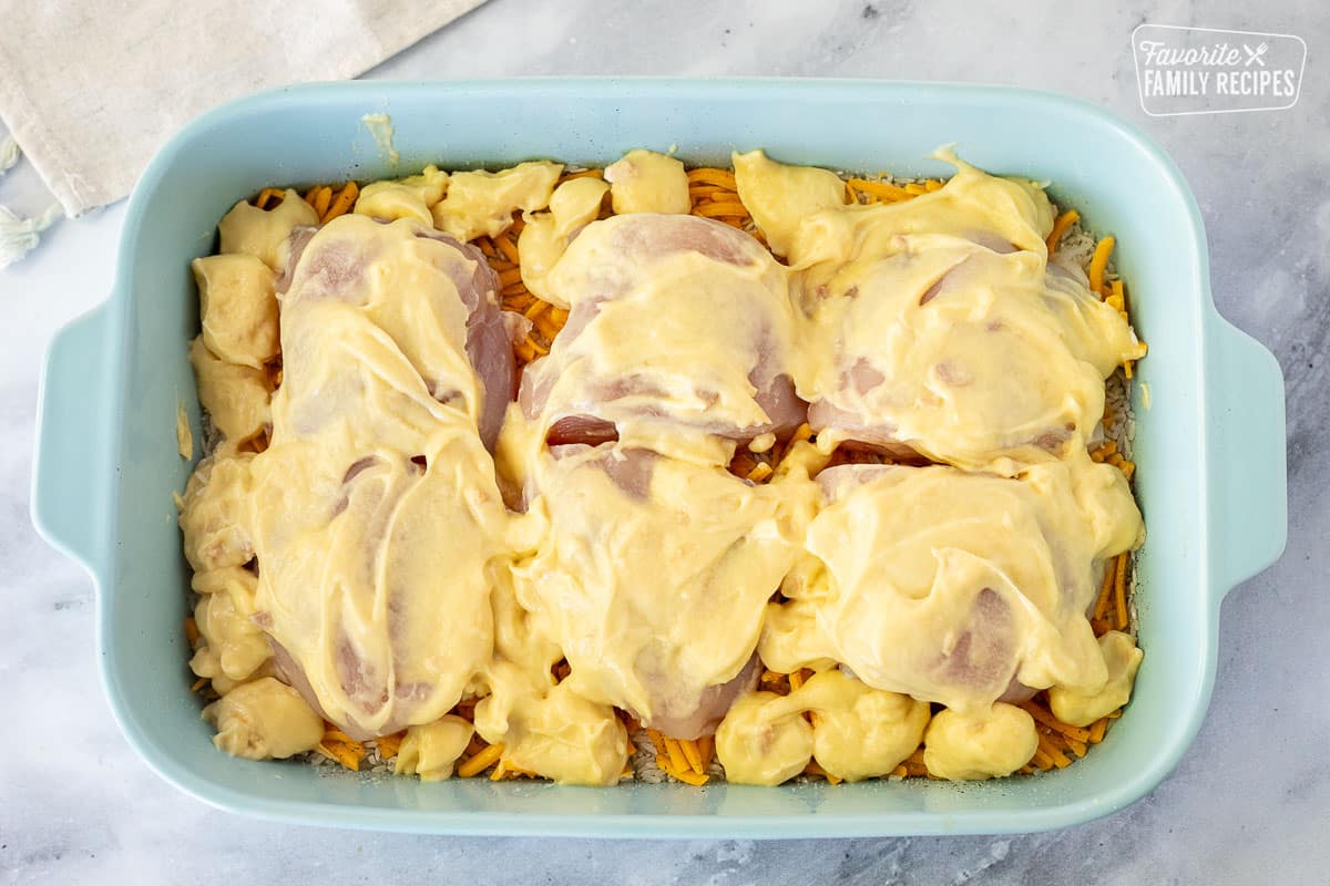 Casserole dish with rice, cheese, chicken, cream of chicken sauce for Cheesy Chicken and Rice Casserole.