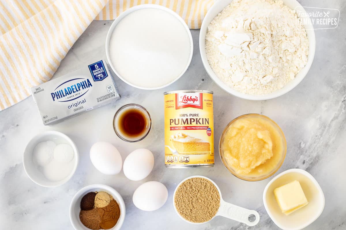 Ingredients to make Pumpkin Cream Cheese Muffins including flour, sugar, cream cheese, dry ingredients, vanilla, eggs, spices, applesauce, butter, brown sugar and pumpkin.