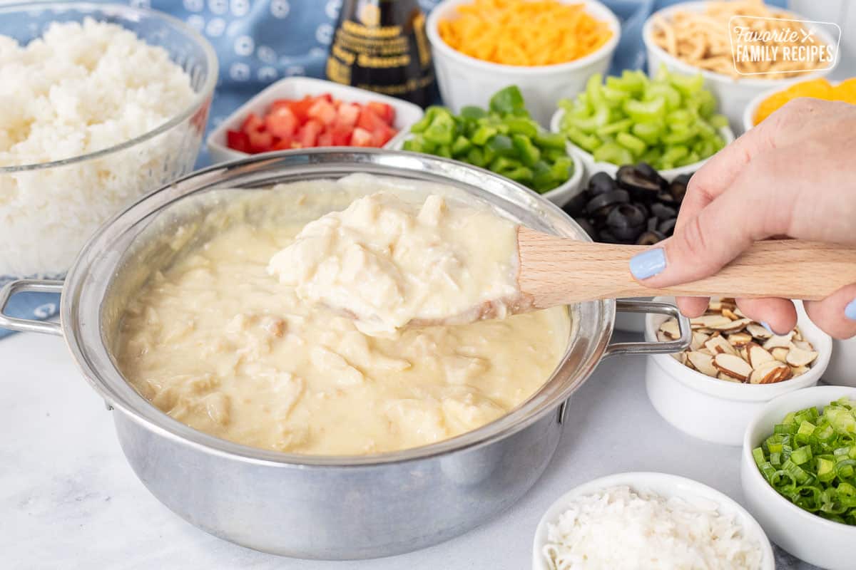 Chicken sauce in a pan for Hawaiian Haystacks. Assortment of topping ingredients behind.