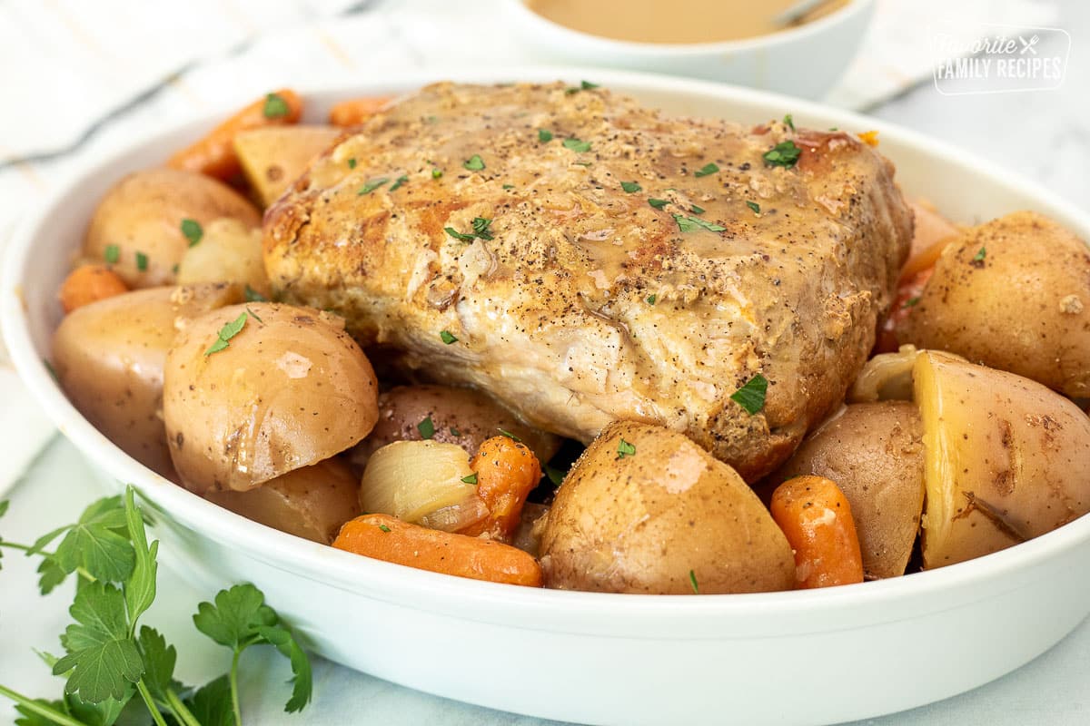 Crock Pot Pork Roast on top of red potatoes and carrots on a platter.