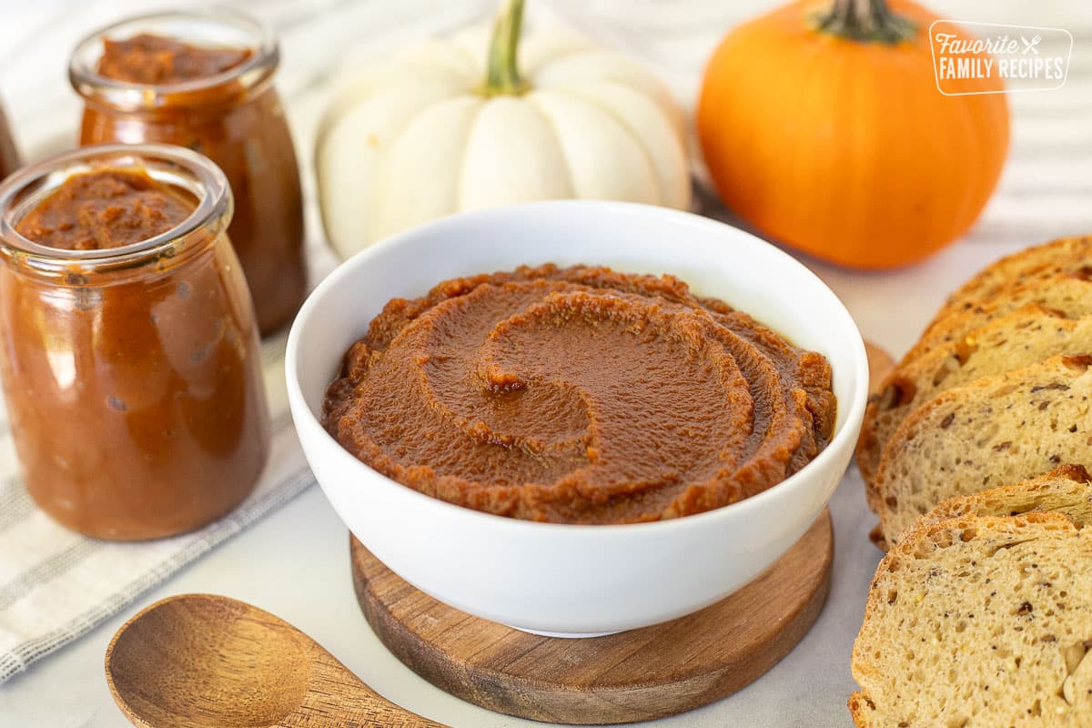 Side view of Pumpkin Butter in a bowl next to bread and jars of Pumpkin Butter.