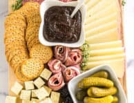 simple charcuterie board with meat, cheese, pickles, blackberries, crackers, and fig butter